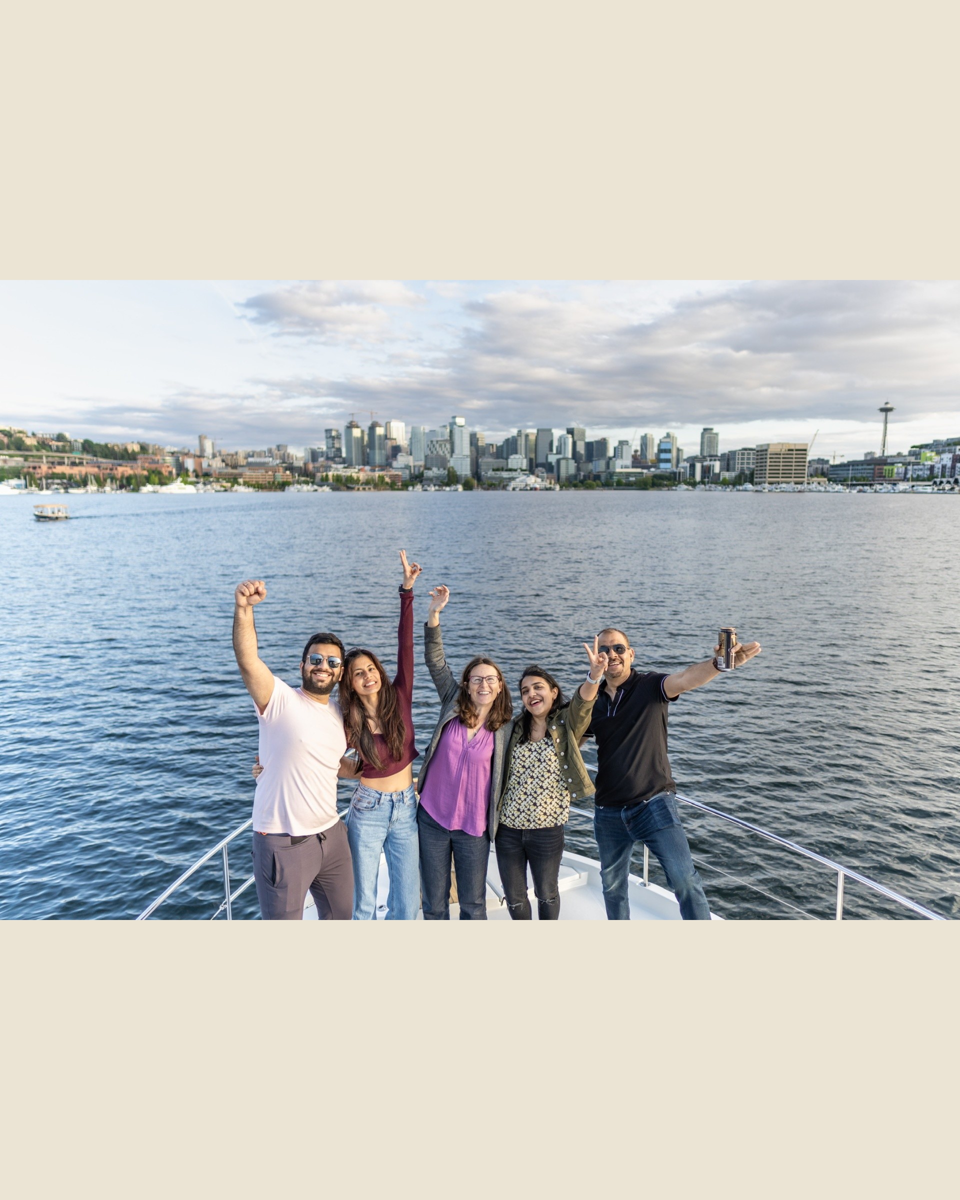 Guests cheering on the bow with the Seattle skyline and Space Needle behind them
